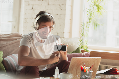 Image of Young man studying at home during online courses for programmer, bug-tester, consulter