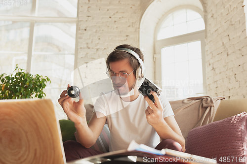 Image of Young man studying at home during online courses for photographer, studio assistant