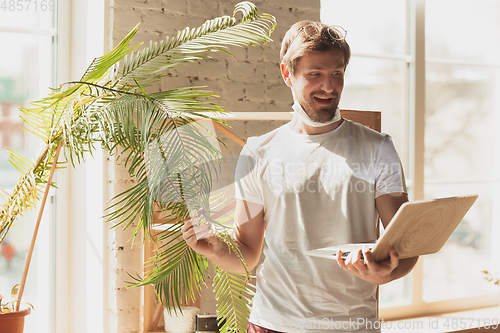 Image of Young man studying at home during online courses for gardener, biologist, florist