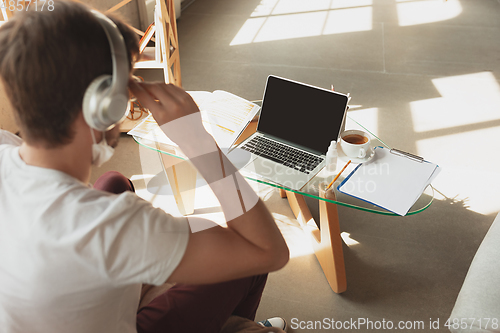 Image of Young man studying at home during online courses for retailer, buyer, teacher