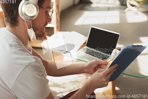 Image of Young man studying at home during online courses for laborer, journalist, developer.