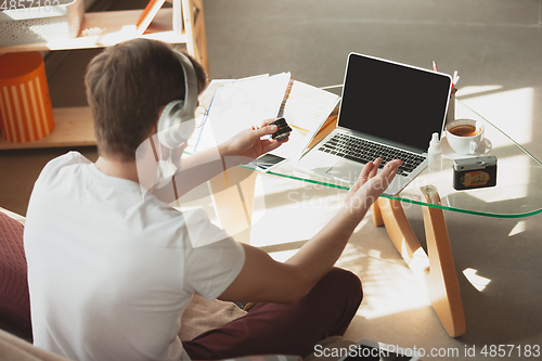 Image of Young man studying at home during online courses for photographer, studio assistant