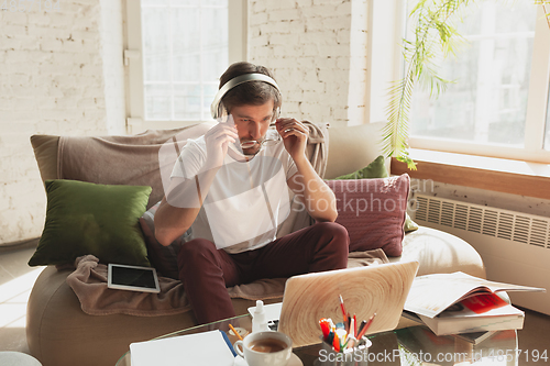 Image of Young man studying at home during online courses for programmer, bug-tester, consulter