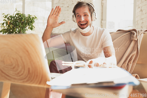 Image of Young man studying at home during online courses for musician, drummer, producer