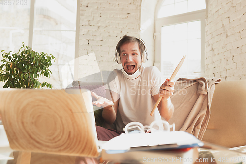 Image of Young man studying at home during online courses for musician, drummer, producer