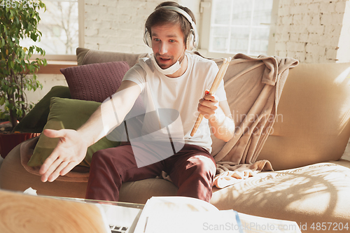 Image of Young man studying at home during online courses for musician, drummer, producer