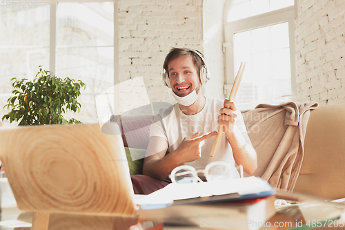 Image of Young man studying at home during online courses for musician, drummer, producer