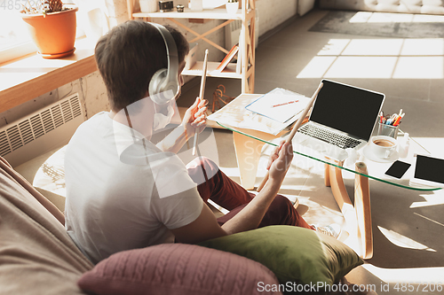 Image of Young man studying at home during online courses for musician, drummer, producer