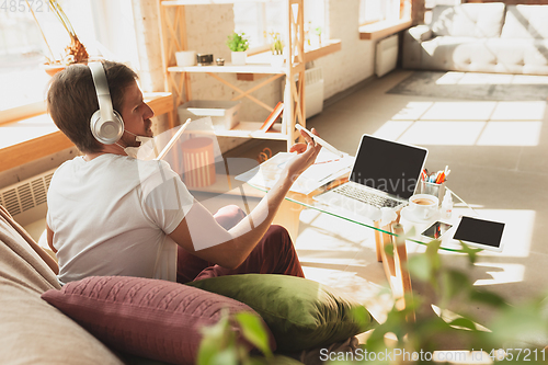 Image of Young man studying at home during online courses for musician, drummer, producer