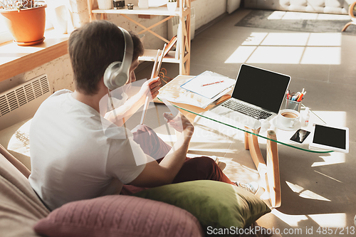 Image of Young man studying at home during online courses for musician, drummer, producer