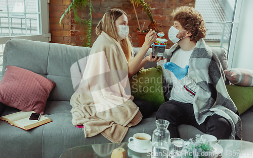 Image of Woman and man, couple in protective masks and gloves isolated at home with coronavirus symptoms