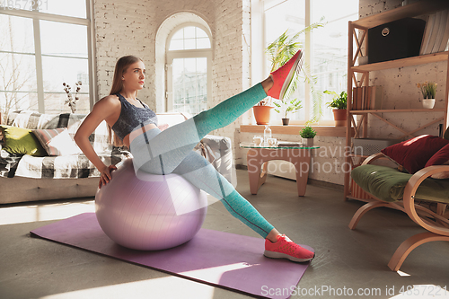 Image of Young woman teaching at home online courses of fitness, aerobic, sporty lifestyle while being quarantine