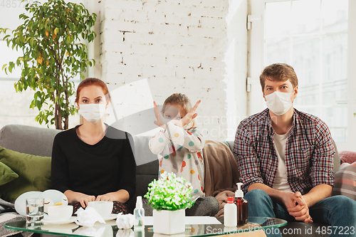 Image of Caucasian family in protective masks and gloves isolated at home with coronavirus symptoms, stop epidemic