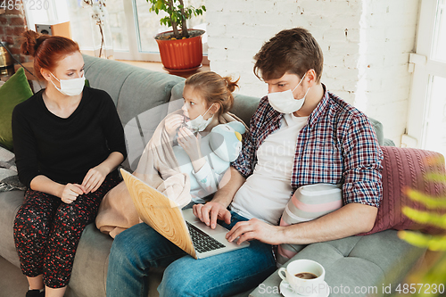 Image of Caucasian family in protective masks and gloves isolated at home with coronavirus symptoms, treatment