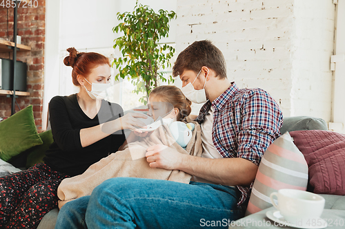 Image of Caucasian family in protective masks and gloves isolated at home with coronavirus symptoms, treatment