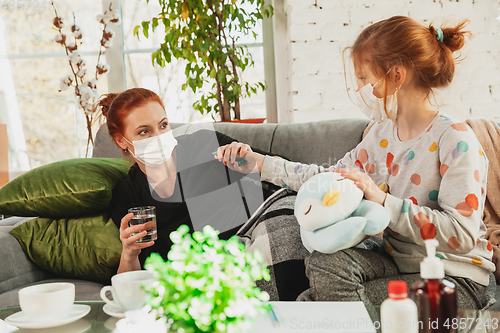 Image of Mother and daughter in protective masks and gloves isolated at home with coronavirus symptoms, stop epidemic