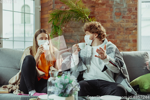 Image of Woman and man, couple in protective masks and gloves isolated at home with coronavirus symptoms