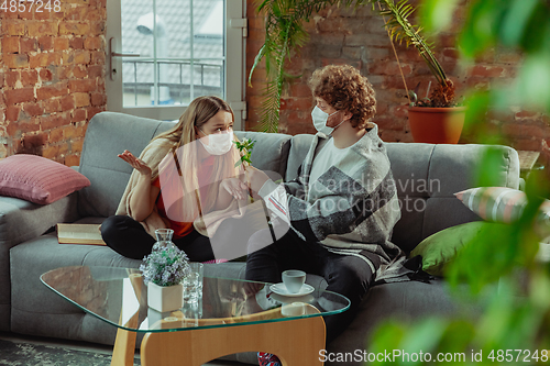 Image of Woman and man, couple in protective masks and gloves isolated at home with coronavirus symptoms