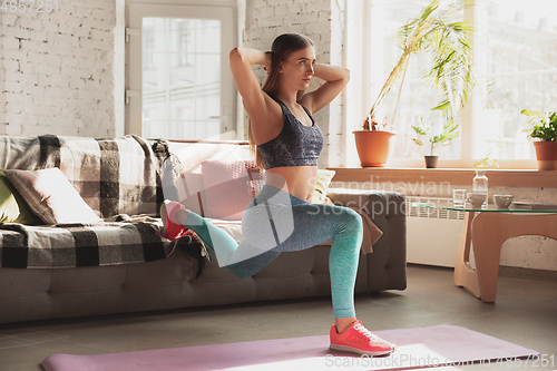 Image of Young woman teaching at home online courses of fitness, aerobic, sporty lifestyle while being quarantine