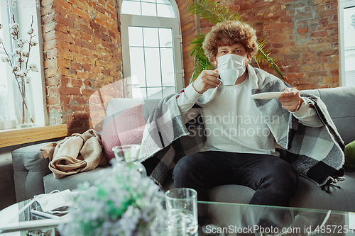 Image of Caucasian man in protective mask and glove isolated at home with coronavirus symptoms