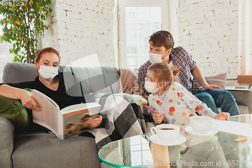 Image of Caucasian family in protective masks and gloves isolated at home with coronavirus symptoms, treatment