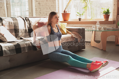 Image of Young woman teaching at home online courses of fitness, aerobic, sporty lifestyle while being quarantine