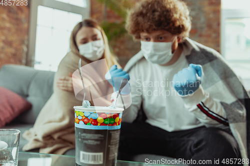 Image of Woman and man, couple in protective masks and gloves isolated at home with coronavirus symptoms