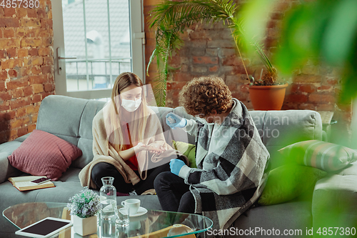 Image of Woman and man, couple in protective masks and gloves isolated at home with coronavirus symptoms