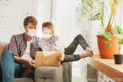 Image of Father and daughter in protective masks and gloves isolated at home with coronavirus symptoms, stop epidemic