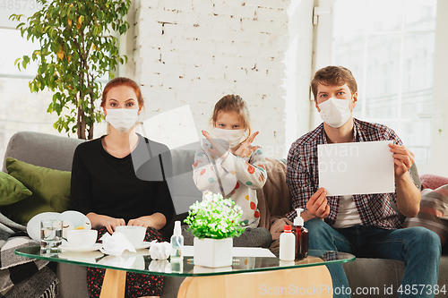 Image of Caucasian family in protective masks and gloves isolated at home with coronavirus symptoms, stop epidemic