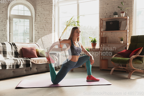 Image of Young woman teaching at home online courses of fitness, aerobic, sporty lifestyle while being quarantine