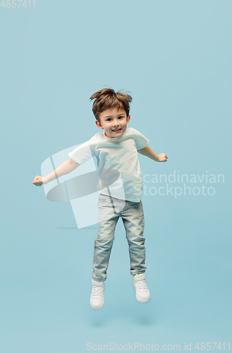 Image of Happy caucasian little boy isolated on blue studio background. Looks happy, cheerful, sincere. Copyspace. Childhood, education, emotions concept