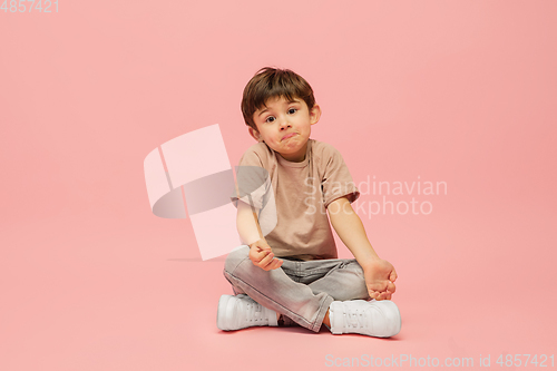 Image of Happy caucasian little boy isolated on pink studio background. Looks happy, cheerful, sincere. Copyspace. Childhood, education, emotions concept