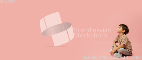 Image of Happy caucasian little boy isolated on pink studio background. Looks happy, cheerful, sincere. Copyspace. Childhood, education, emotions concept