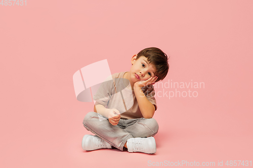 Image of Happy caucasian little boy isolated on pink studio background. Looks happy, cheerful, sincere. Copyspace. Childhood, education, emotions concept