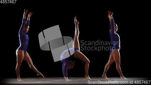 Image of Young flexible girl on black studio background in strobe and neon light. Young female model practicing artistic gymnastics.