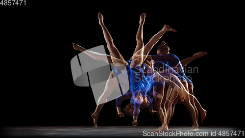 Image of Young flexible girl on black studio background in strobe and neon light. Young female model practicing artistic gymnastics.