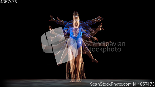 Image of Young flexible girl on black studio background in strobe and neon light. Young female model practicing artistic gymnastics.