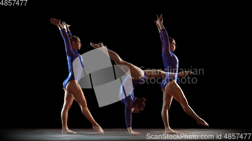 Image of Young flexible girl on black studio background in strobe and neon light. Young female model practicing artistic gymnastics.