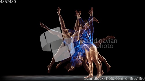 Image of Young flexible girl on black studio background in strobe and neon light. Young female model practicing artistic gymnastics.