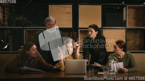 Image of Young colleagues working together in a office styled like classical artworks. Look busy, attented, cheerful, successful. Concept of business, office, finance.