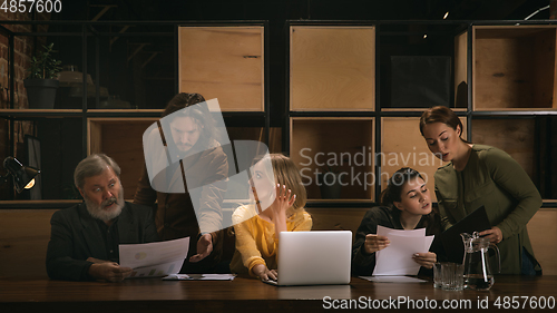 Image of Young colleagues working together in a office styled like classical artworks. Look busy, attented, cheerful, successful. Concept of business, office, finance.