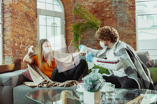 Image of Woman and man, couple in protective masks and gloves isolated at home with coronavirus symptoms