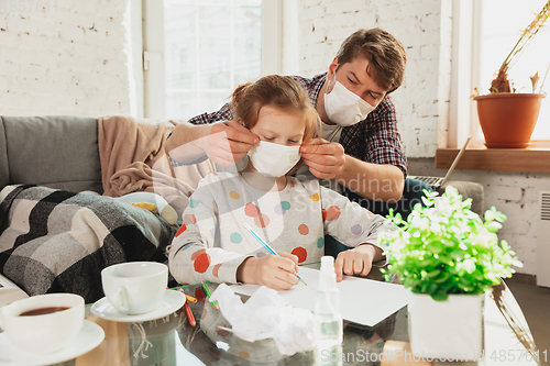 Image of Father and daughter in protective masks and gloves isolated at home with coronavirus symptoms, stop epidemic