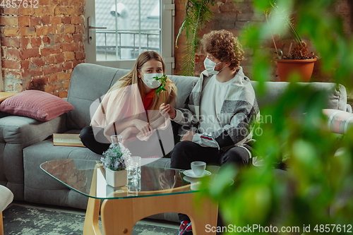 Image of Woman and man, couple in protective masks and gloves isolated at home with coronavirus symptoms