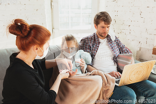 Image of Caucasian family in protective masks and gloves isolated at home with coronavirus symptoms, treatment