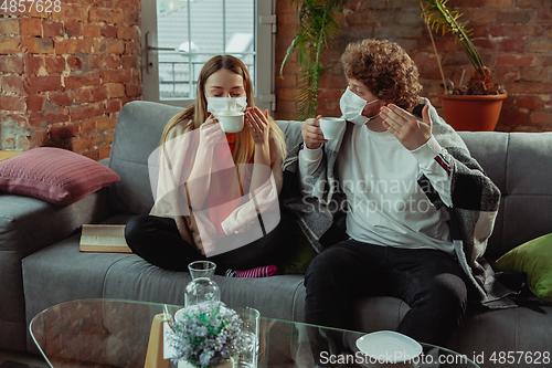 Image of Woman and man, couple in protective masks and gloves isolated at home with coronavirus symptoms