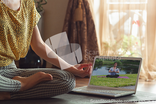 Image of Sporty young woman taking yoga lessons online and practice at home while being quarantine