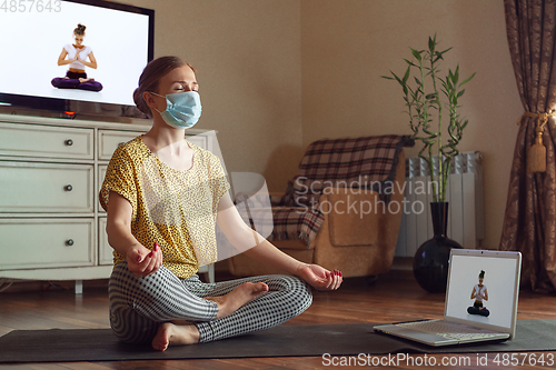 Image of Sporty young woman taking yoga lessons online and practice at home while being quarantine