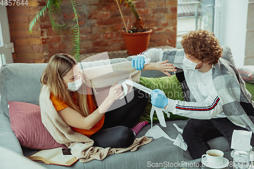 Image of Woman and man, couple in protective masks and gloves isolated at home with coronavirus symptoms